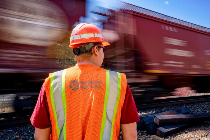 A BNSF grain train passes by an MRL employee